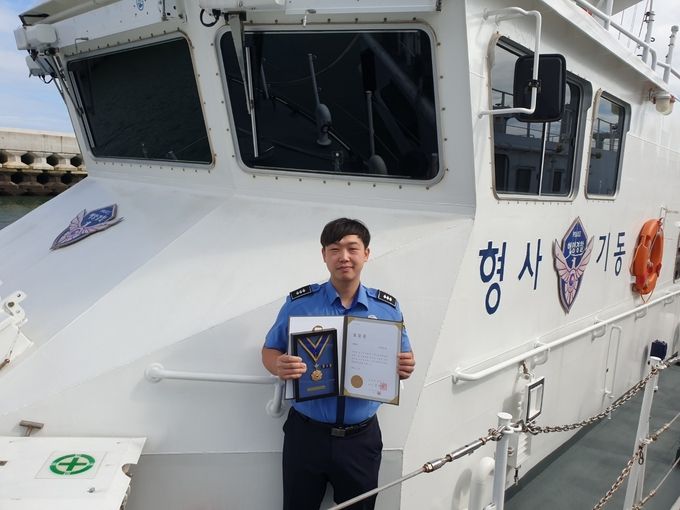 형사기동정 P-120정에서 근무하는 나문선 경장이 100회를 기념하는 명예장을 들고 근무하는 함정에서 사진을 찍었다.