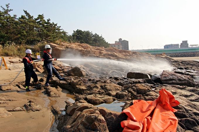 (참고사진)해안가에 떠밀려와 암벽에 붙어있는 기름을 제거하기 이해 고압분사기로 기름을 제거하고 _