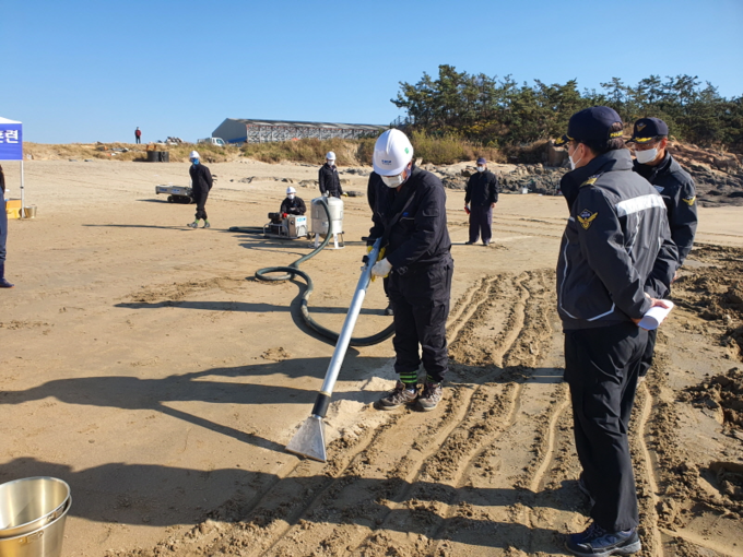 (참고사진)해안가에 떠밀려와 암벽에 붙어있는 기름을 제거하기 이해 고압분사기로 기름을 제거하고 _