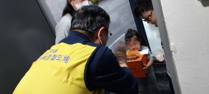 운양동 지역사회보장협의체 회원들이 생일을 맞은 아동을 찾아가 케이크와 손으로 쓴 카드를 전달하고 있다