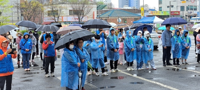 우비를 입은 주민들이 벚꽃 가득한 둘레길 걷기 행사에 앞서 관계자의 안내 사항 등을 경청하고 있다