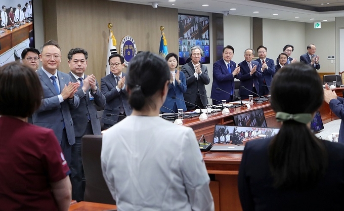 윤석열 대통령과 중대본 위원들이 11일 열린 코로나19 중앙재난안전대책본부 회의에 앞서 코로나19 방역 최전선에서 활약한 현장 의료진에게 격려의 박수를 보내고 있다