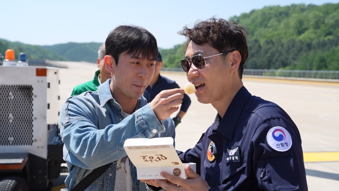 산림헬기 조종사에게 감자떡을 먹이고 있는 한라대학생