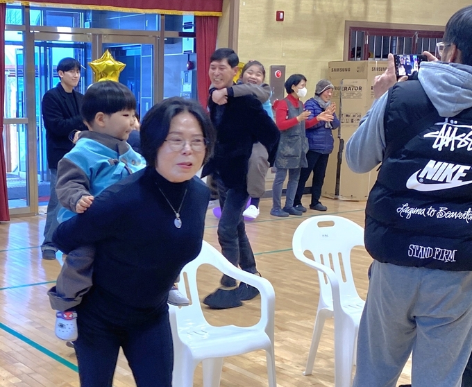 어르신들이 신입생을 업고 강당을 돌며 즐거워하고 있다.