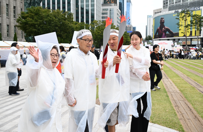 19일(금) 오전 서울광장에서 열린 '제18회 서울시 치매극복의 날 기념행사'에 참석한 시민이 치매동행 이벤트 성화봉송 릴레이에 참여하고 있다